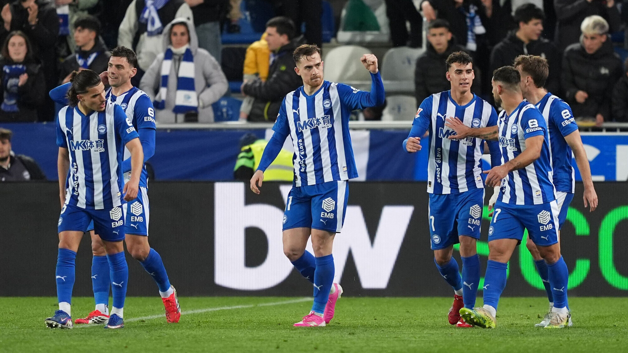 Mavi-beyaz formalı futbolcular sahada galibiyet golünü kutluyor.