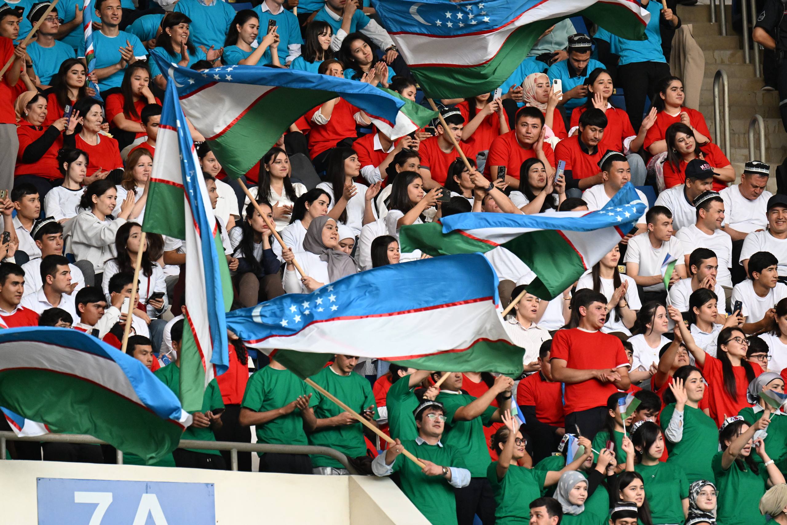 Tribunada yig‘ilgan ko‘plab tomoshabinlar O‘zbekiston bayroqlarini hilpiratmoqdalar.