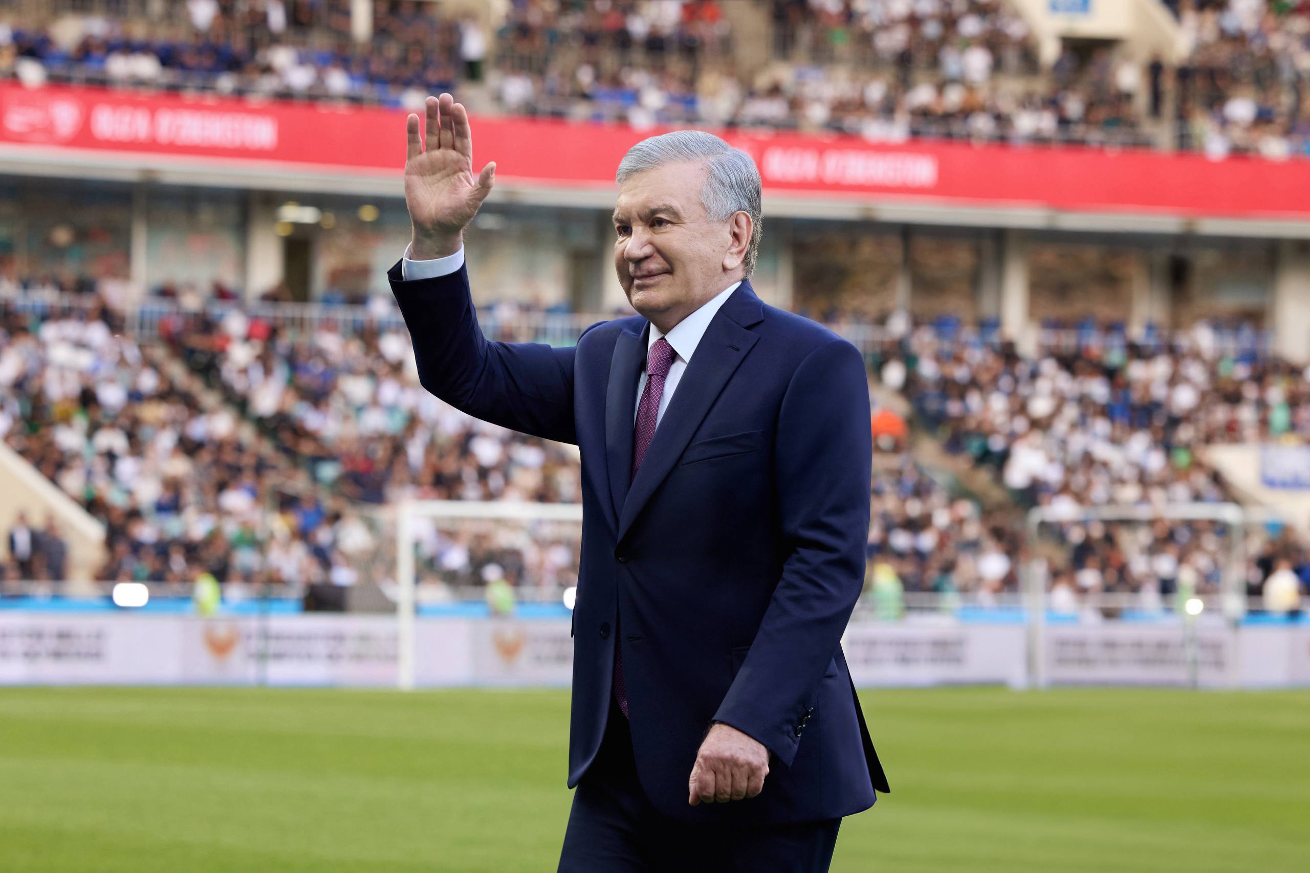 Prezident Shavkat Mirziyoyev stadionda qo‘lini ko‘tarib xalqqa salom bermoqda.