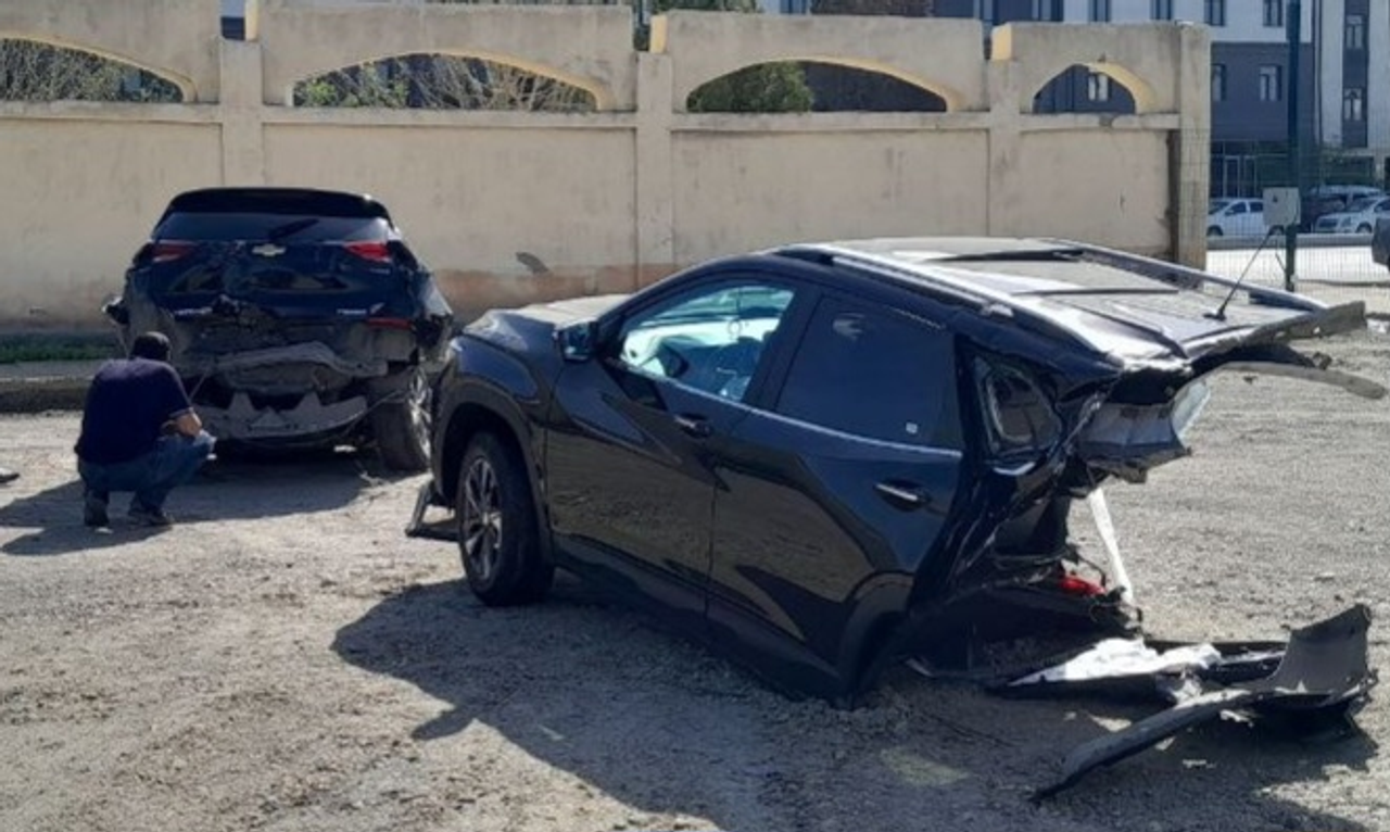 Dos coches negros con la parte trasera destrozada como resultado del accidente y una persona junto a ellos.