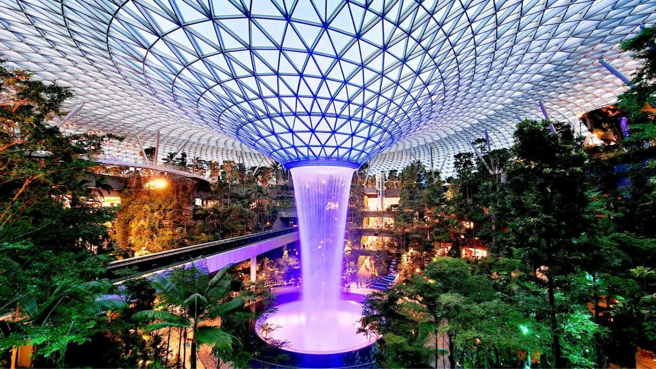 Changi aeroportidagi ulkan shisha gumbaz ostida joylashgan yopiq sharshara va tropik bog'.