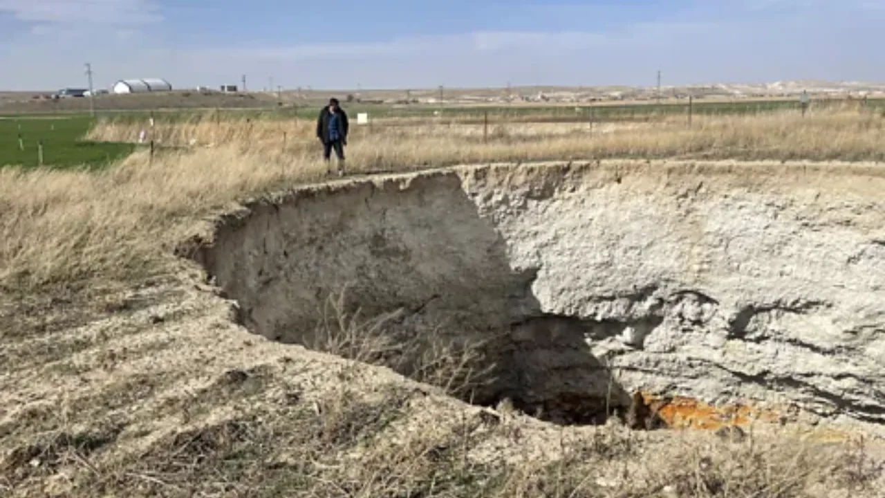 Dala oʻrtasidagi ulkan chuqurlik yoqasida bir kishi turibdi.