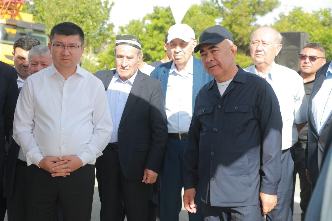 Bir guruh erkaklar ochiq havoda turli xil kiyimlarda birga turishibdi.