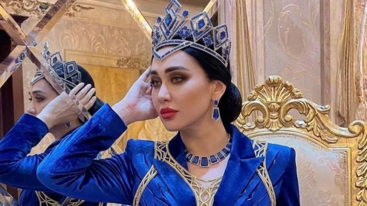 Moviy libos va toj kiygan ayol oyna qarshisida o‘tiribdi.