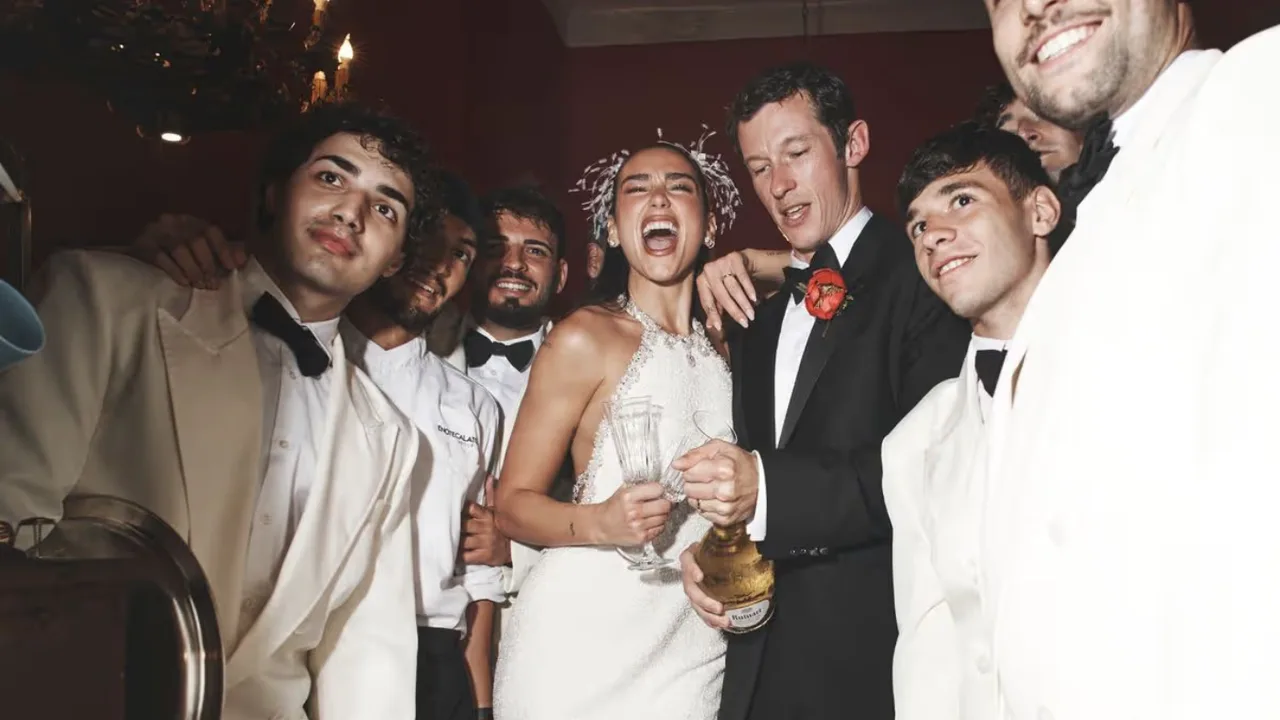 Dua Lipa va yigitlar shodiyona vaqtida shampan vinosini ochishmoqda.