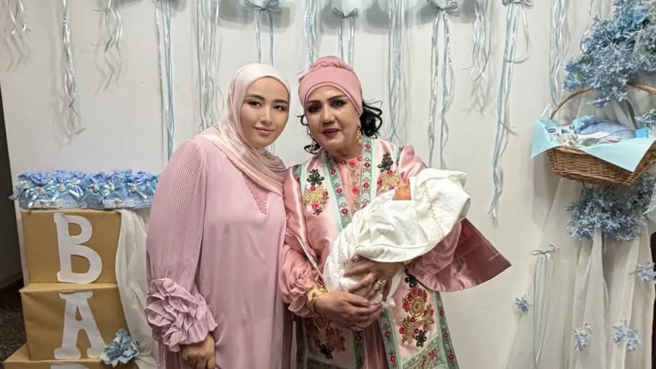 Ikki ayol bayramona muhitda chaqaloq bilan suratga tushmoqda.