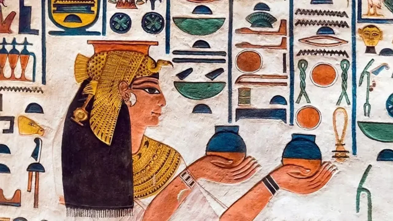 Ierogliflar orasida idish ko'targan qadimgi Misr ayolining devoriy surati.