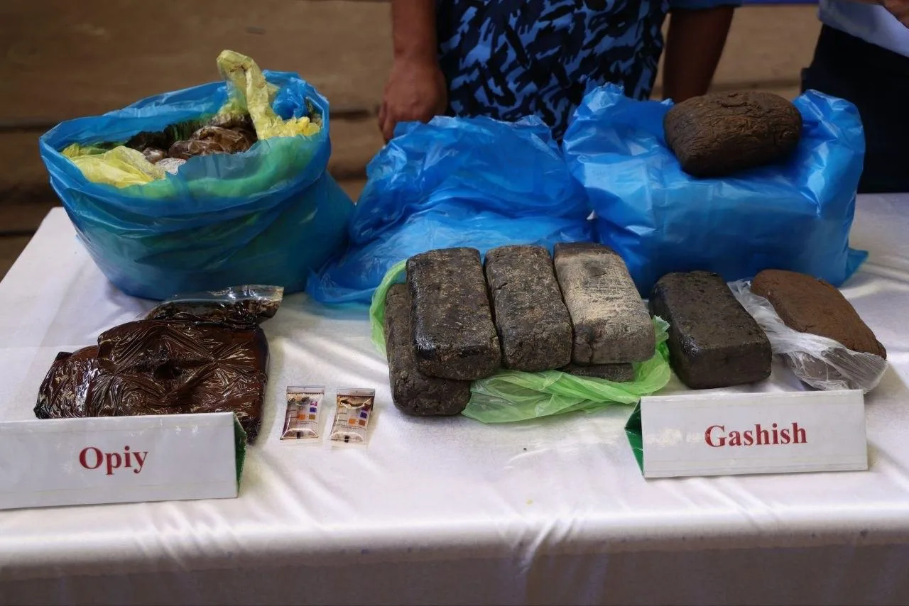 Stol ustida plastik paketlarga solingan opiy va gashish briketlari turibdi.