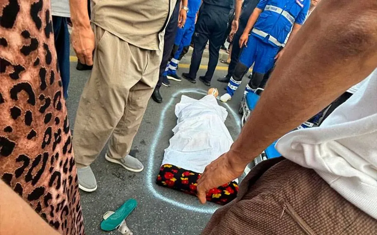People gathered around a body covered with a white sheet on the street.