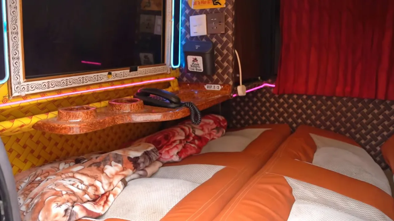 Avtobus salonining yotoq o'rinlari va televizor o'rnatilgan shinam qismi.