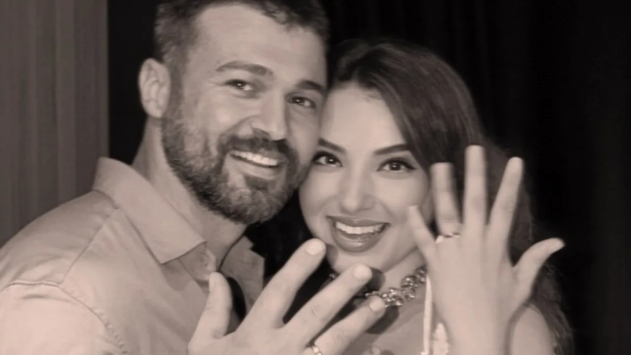 A couple smiling and showing off their rings.