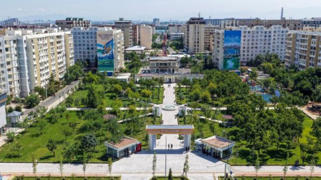Ko‘p qavatli binolar orasida joylashgan yashil istirohat bog‘i.