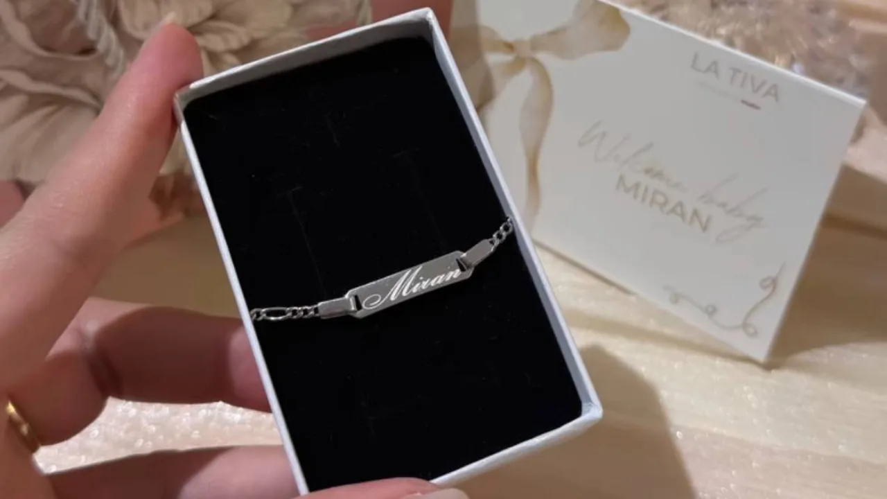 A silver bracelet with the inscription 'Miran' inside a box, along with a greeting card.
