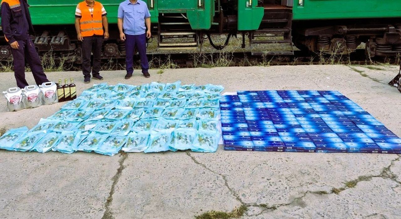 Poyezd yonida yerga terib qo‘yilgan ko‘plab kontrabanda tovarlar va uch nafar erkak.
