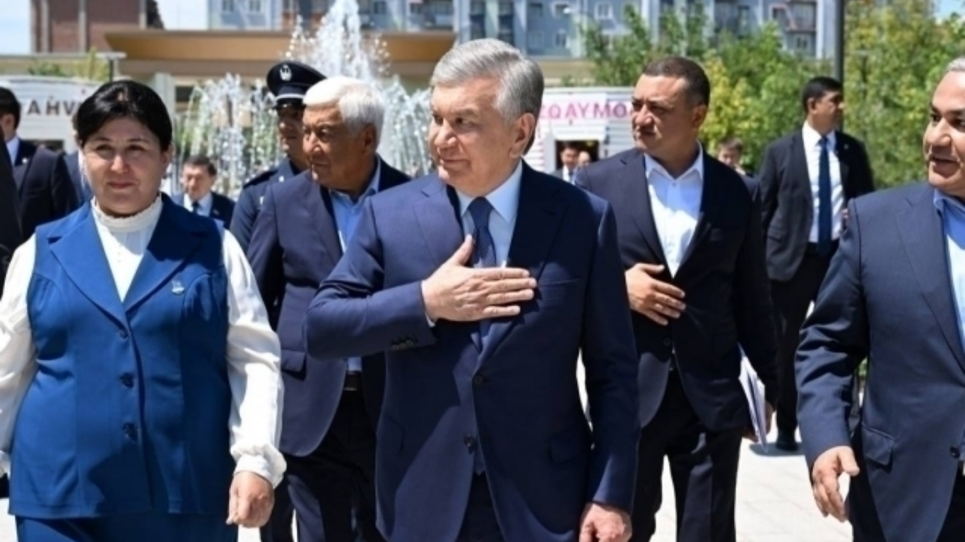 Shavkat Mirziyoyev hamrohlar davrasida qo‘lini ko‘ksiga qo‘yib yurib bormoqda.