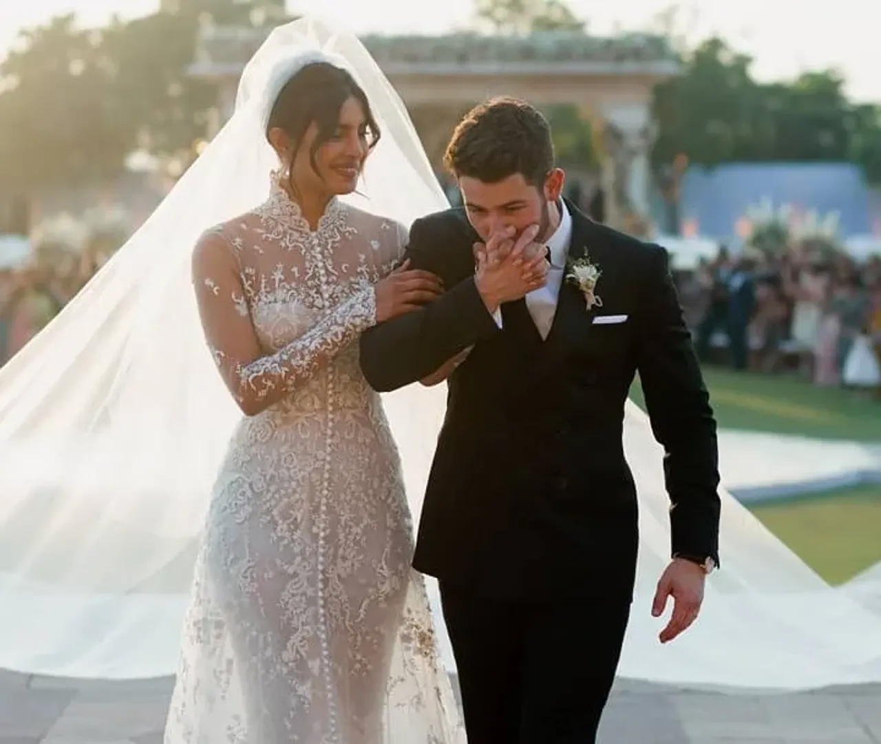 Nick Jonas kissing Priyanka Chopra's hand while walking together at the wedding ceremony.