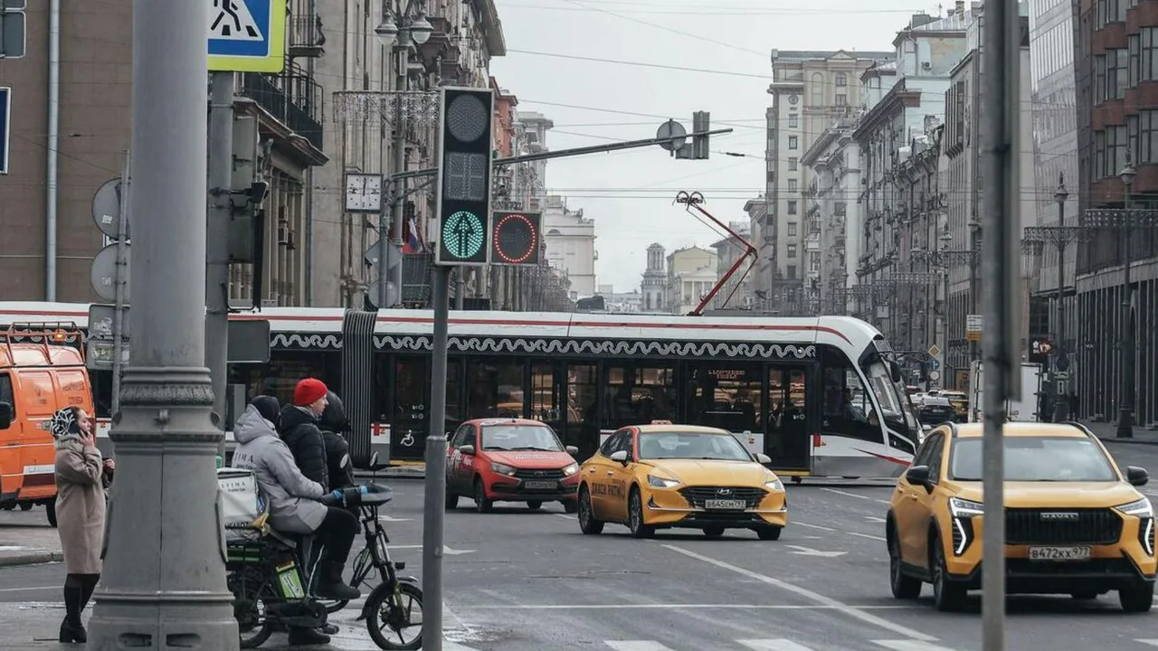 Shahar ko‘chasida harakatlanayotgan avtomobillar, tramvay va svetofor.