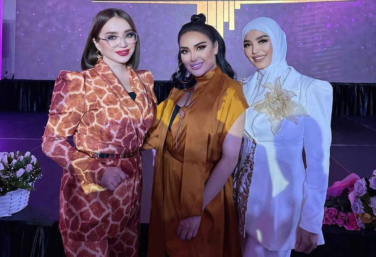 Bayramona libosdagi uch ayol sahnada jilmayib turibdi.