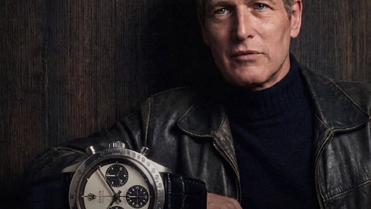 Ko'n kurtka kiygan erkak va uning yonida katta Rolex soati tasvirlangan.