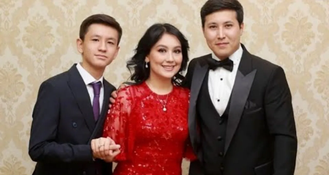 Kostyumdagi ikki yigit va qizil ko‘ylakdagi ayol birga rasmga tushmoqda.