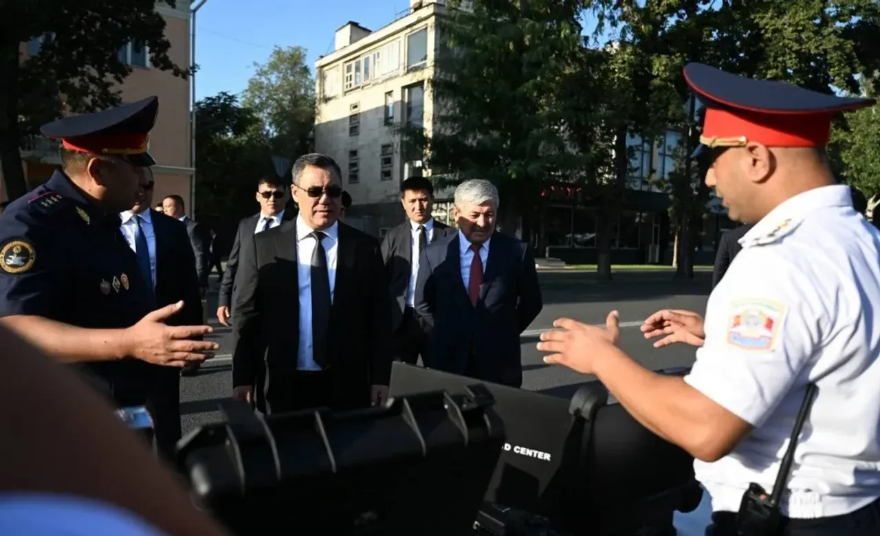 Kostyumdagi erkaklar guruhiga politsiya xodimlari ko‘chada nimadir namoyish qilmoqda.