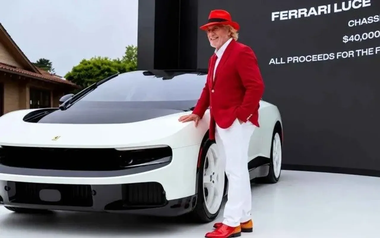 Qizil kostyumli kishi oq rangli Ferrari Luce avtomobili yonida turibdi.