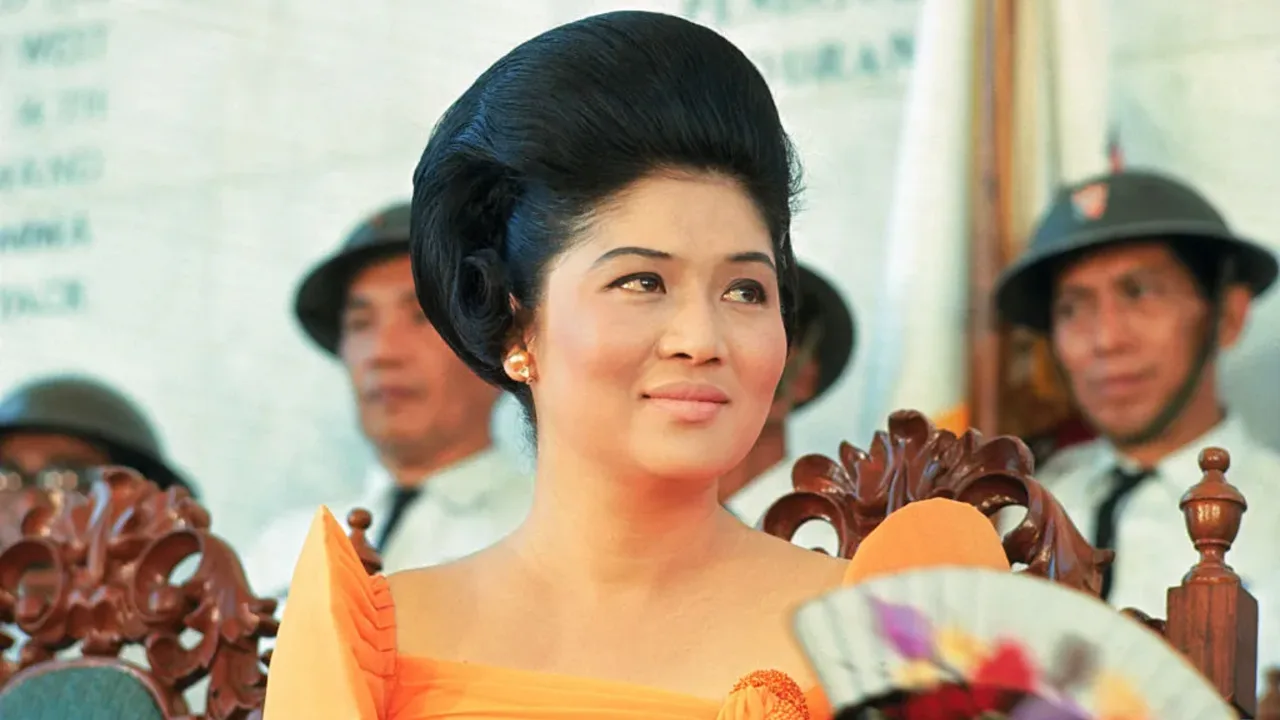Imelda Marcos o'ziga xos soch turmagi va zargarlik buyumlari bilan ochiq havoda turibdi.