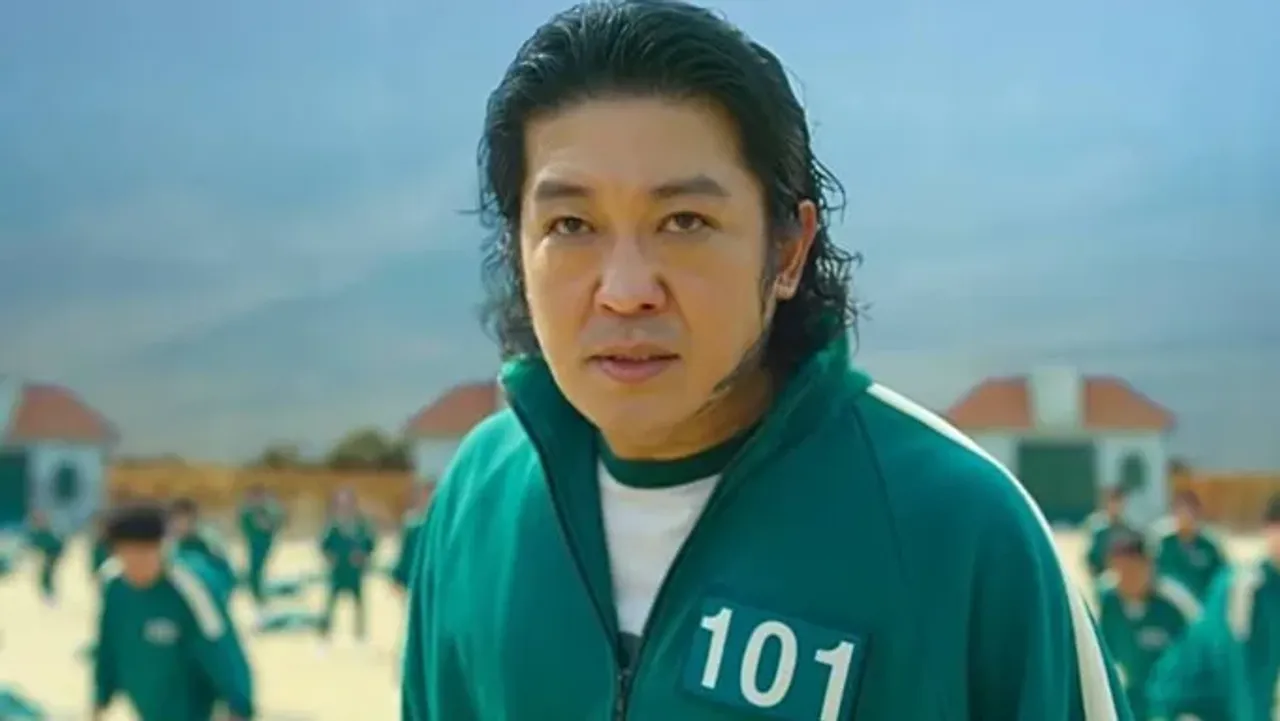 101 raqamli yashil sport kiyimidagi Jang Deok-su obrazining yaqindan ko'rinishi.