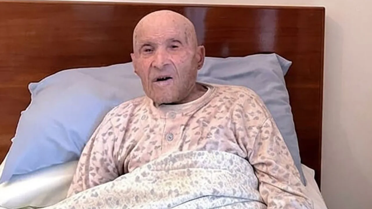 Keks yoshdagi, boshi kal kishi karavotda o‘tirib gapirmoqda.