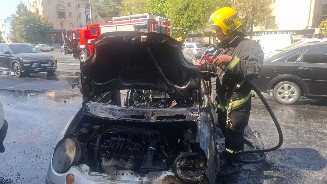 O‘t o‘chiruvchi ko‘chada yonib ketgan avtomobilning motor qismini ko‘zdan kechirmoqda.