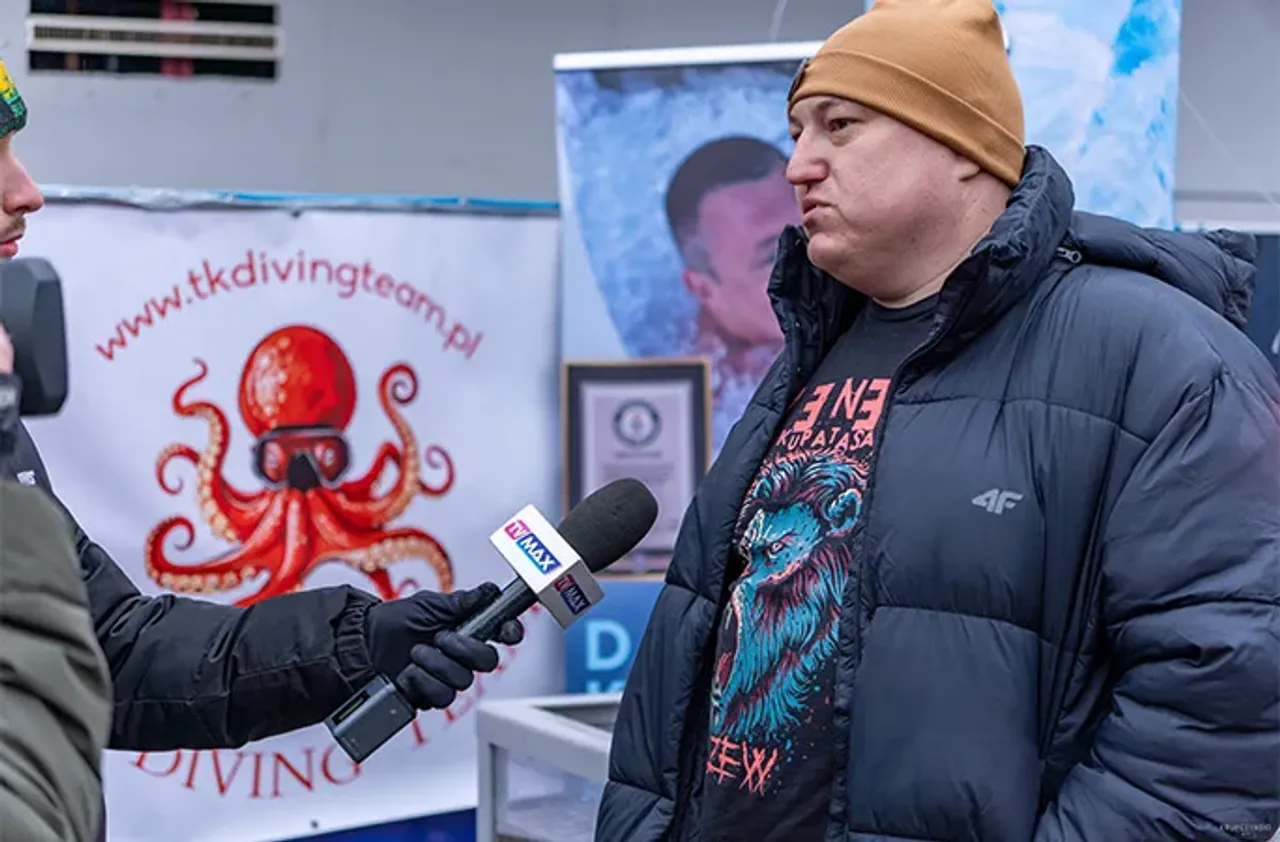 Jigarrang qalpoqli kishi mikrofon tutgan muxbirga intervyu bermoqda.