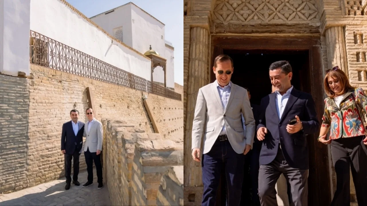 Ikki kishi qadimiy g‘ishtli devor yonida va binodan chiqishda turibdi.
