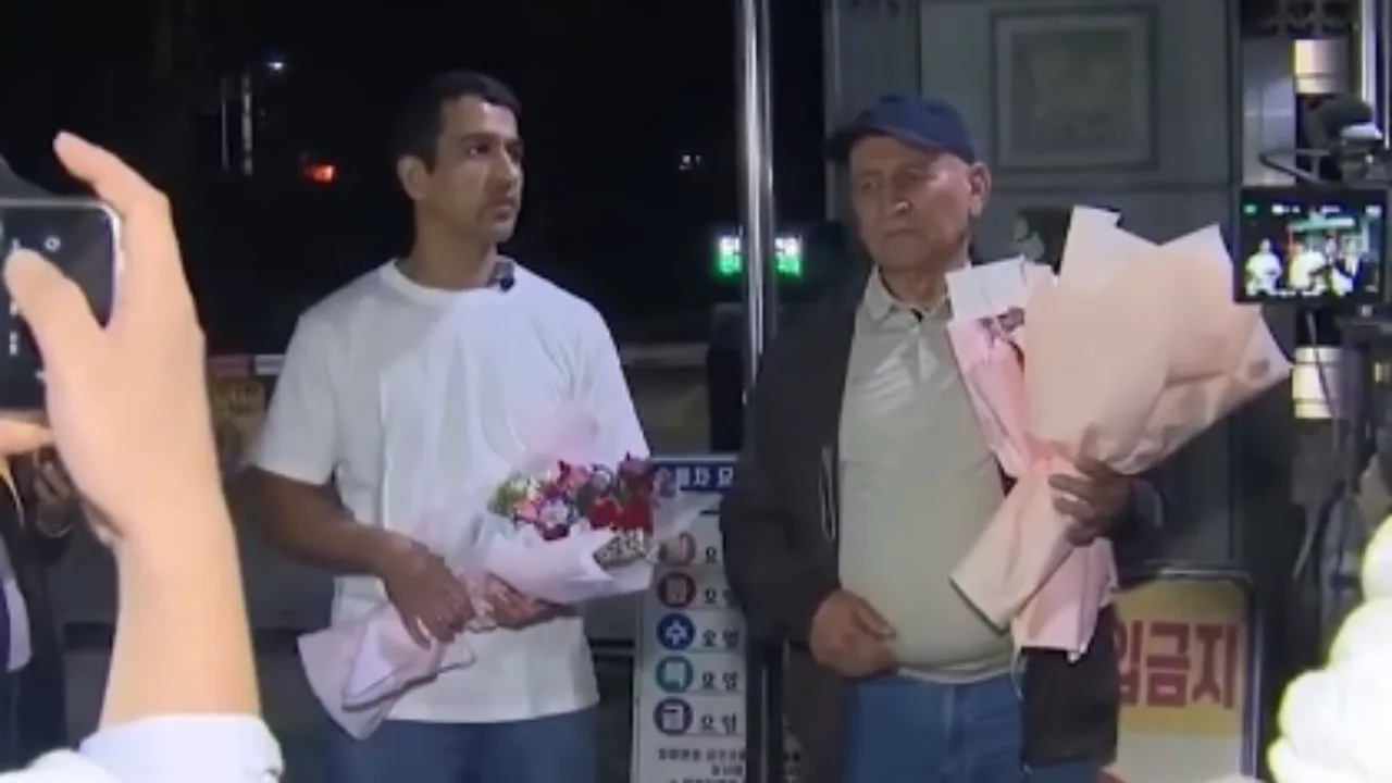 Ikki kishi qo‘lida guldasta bilan kameralar qarshisida turibdi.