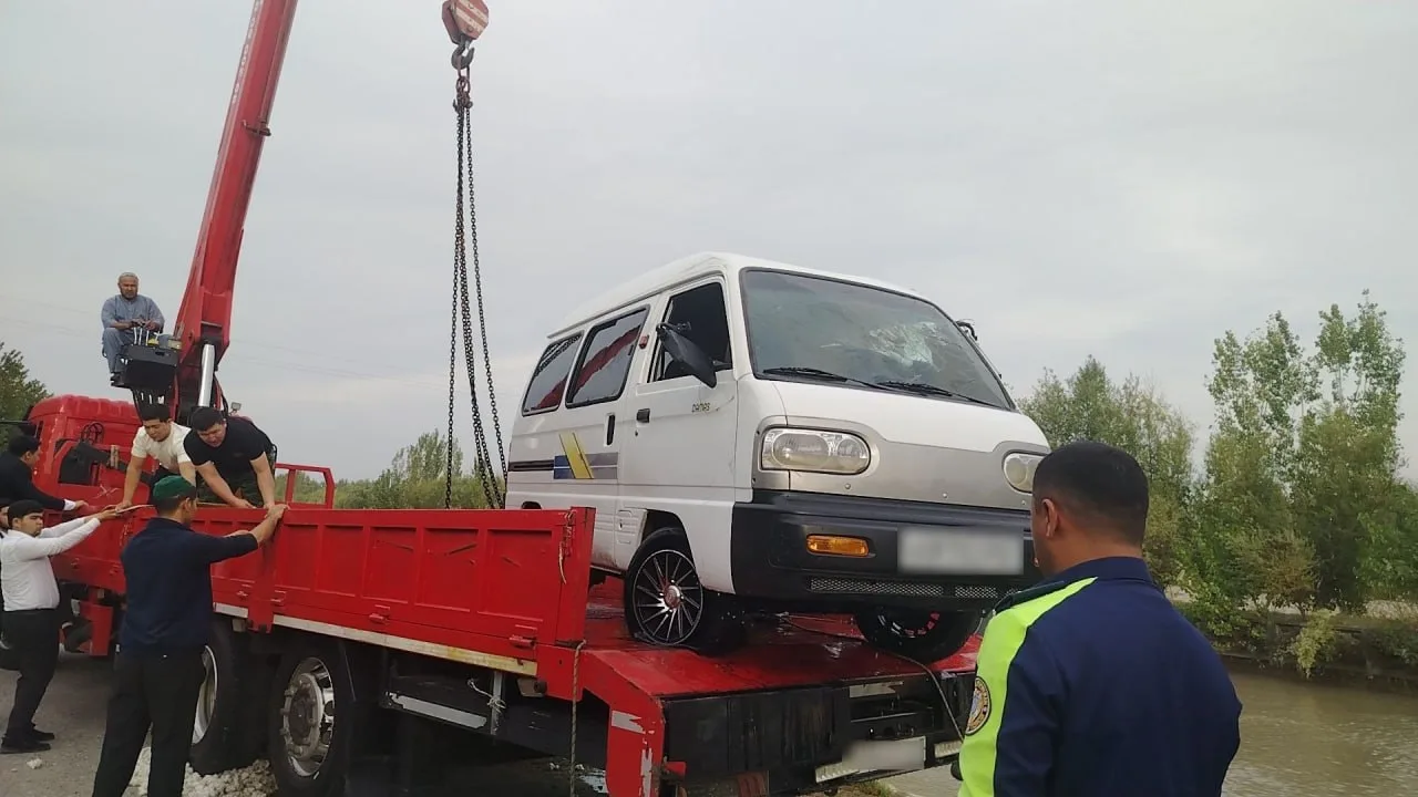 A red crane loading a white Damas car onto a truck.
