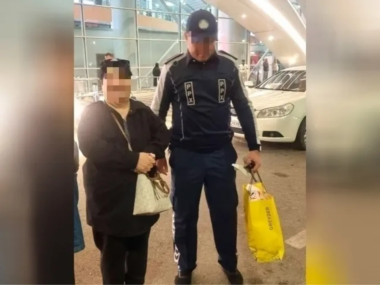 PPX xodimi ko'chada ayol kishining sumkalarini ko'tarib ketmoqda.
