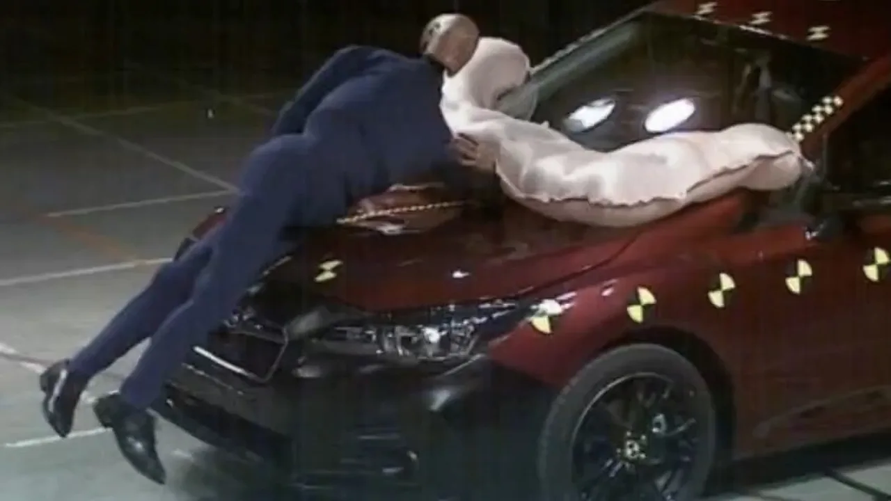 An airbag installed on the front hood of a car hitting a dummy during a crash test.