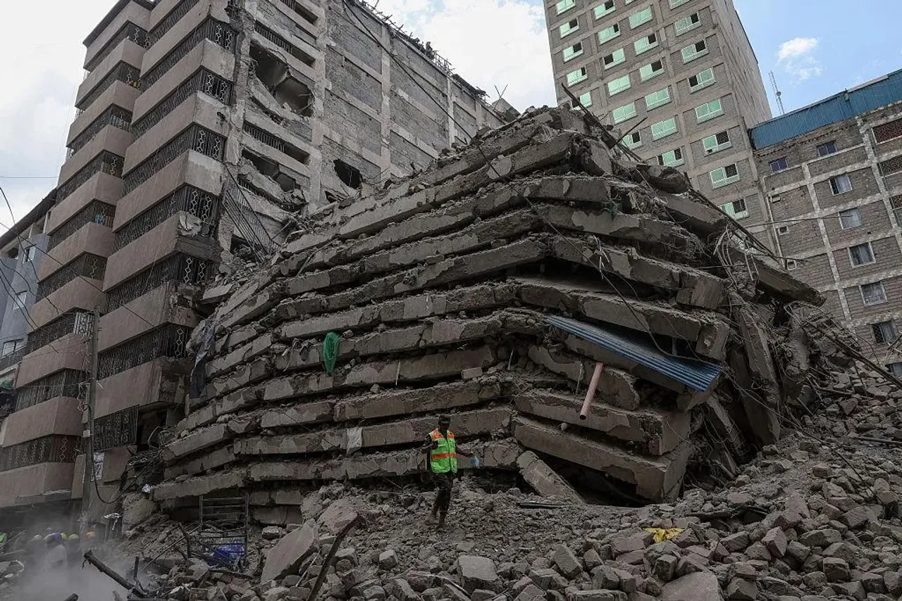 A rescuer stands near the remains of the collapsed multistory building.