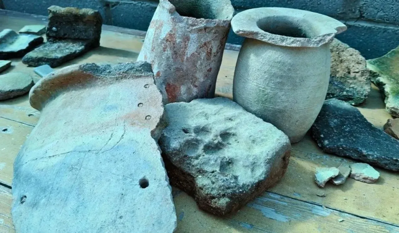 Various ancient ceramic vessels and stone fragments on a wooden surface.