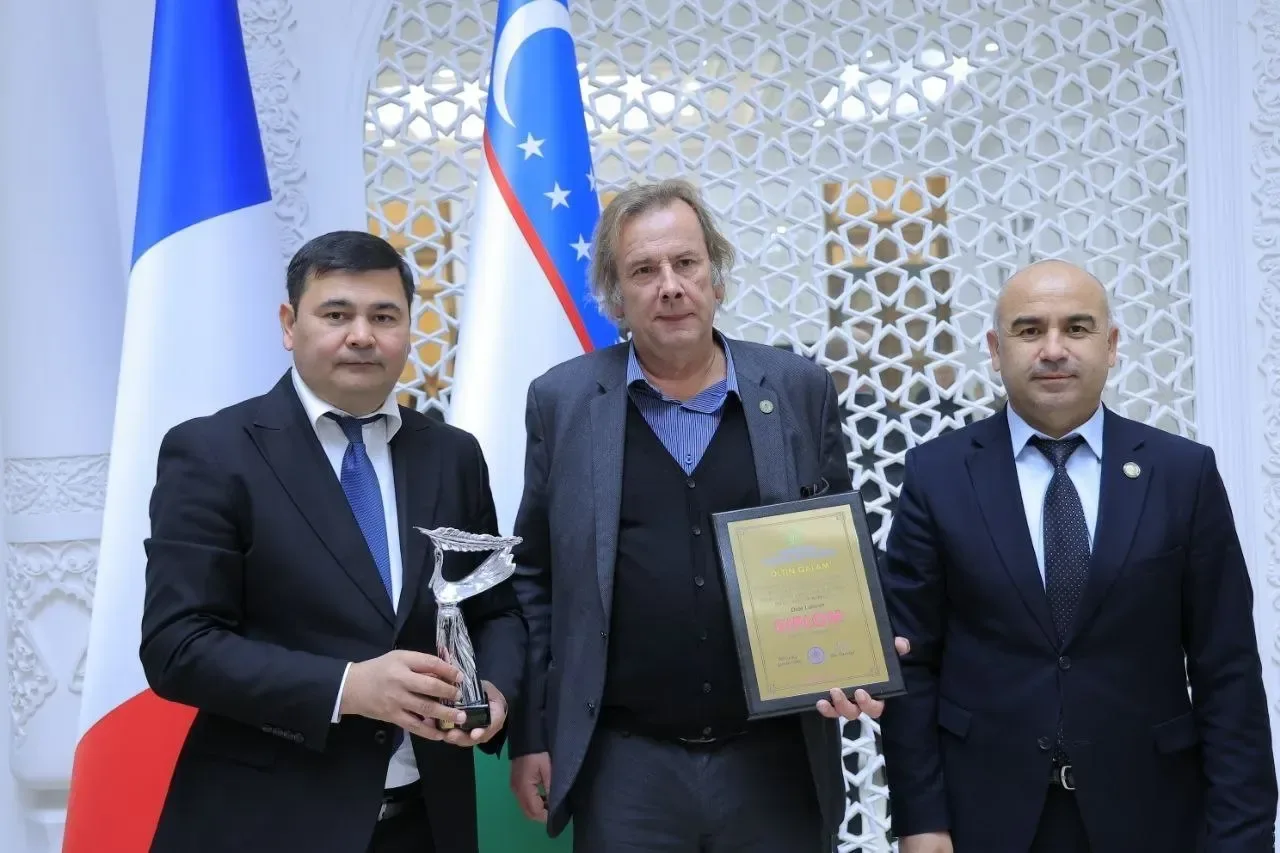 Uch nafar erkak Fransiya va O‘zbekiston bayroqlari oldida mukofotlar bilan turibdi.