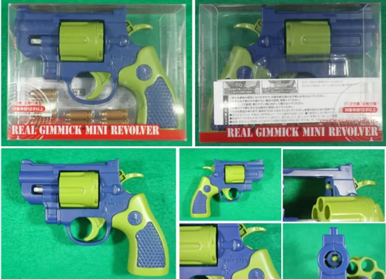 Qutida va undan tashqarida ko‘k va yashil rangli o‘yinchoq mini revolver.