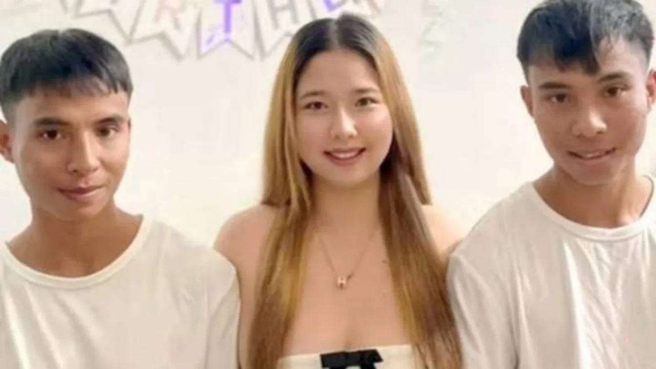 A woman in white and two men smiling in front of a white wall.